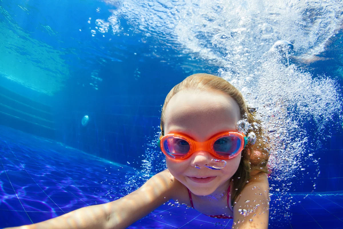 Ein Kind mit Schwimmbrille taucht Unterwasser